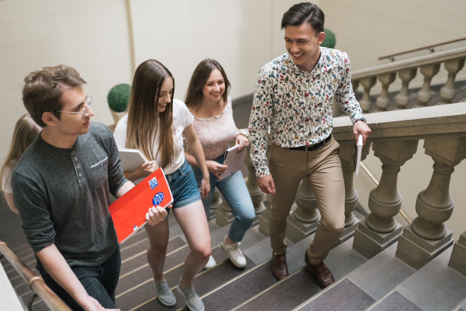 Grupa studentów z teczkami wchodzi do biblioteki