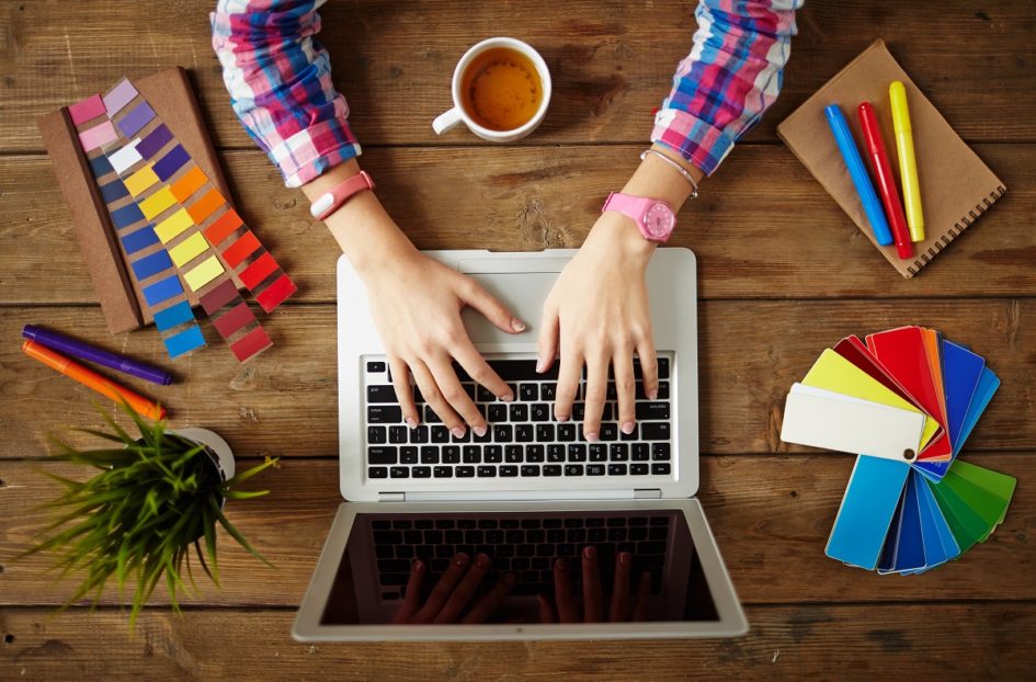Ręce na laptopie w otoczeniu kolorowych kartek